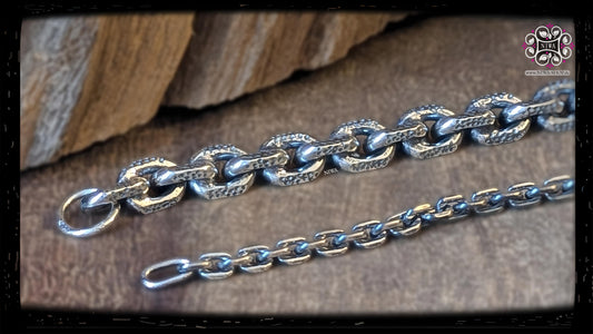 Detailed view of BREEZE: solid links with fine round recesses and shiny polished surfaces, next to them a delicate chain half.