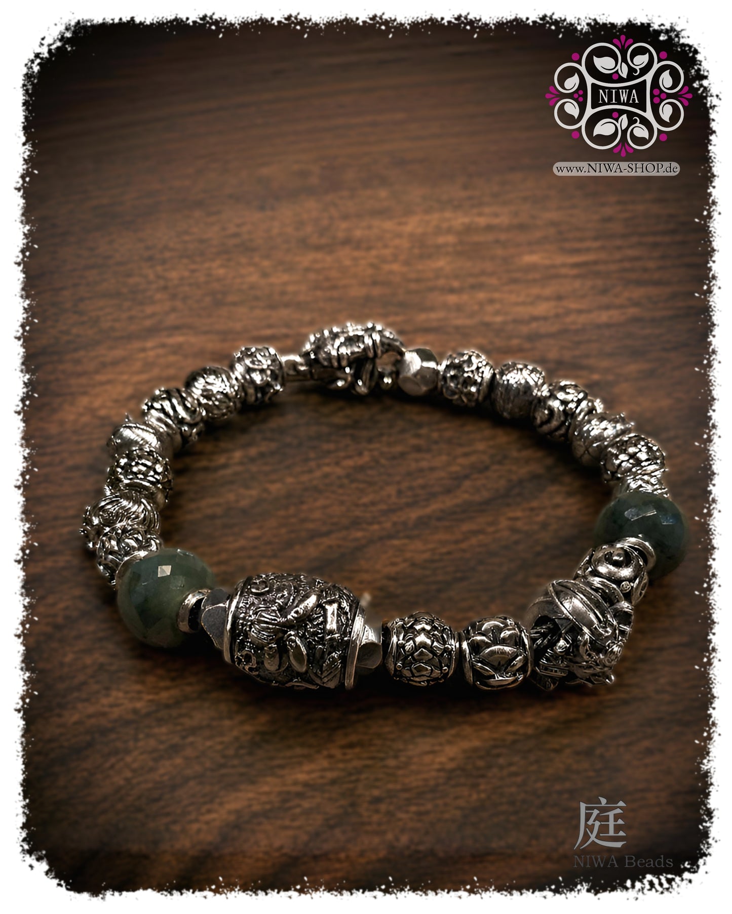 Armband mit Phra Pidta Charm BLIND BUDDHIST aus massivem 925 SterlingSilber, kombiniert mit silbernen NIWABeads und grünen Edelsteinbeads auf dunklem Holz.