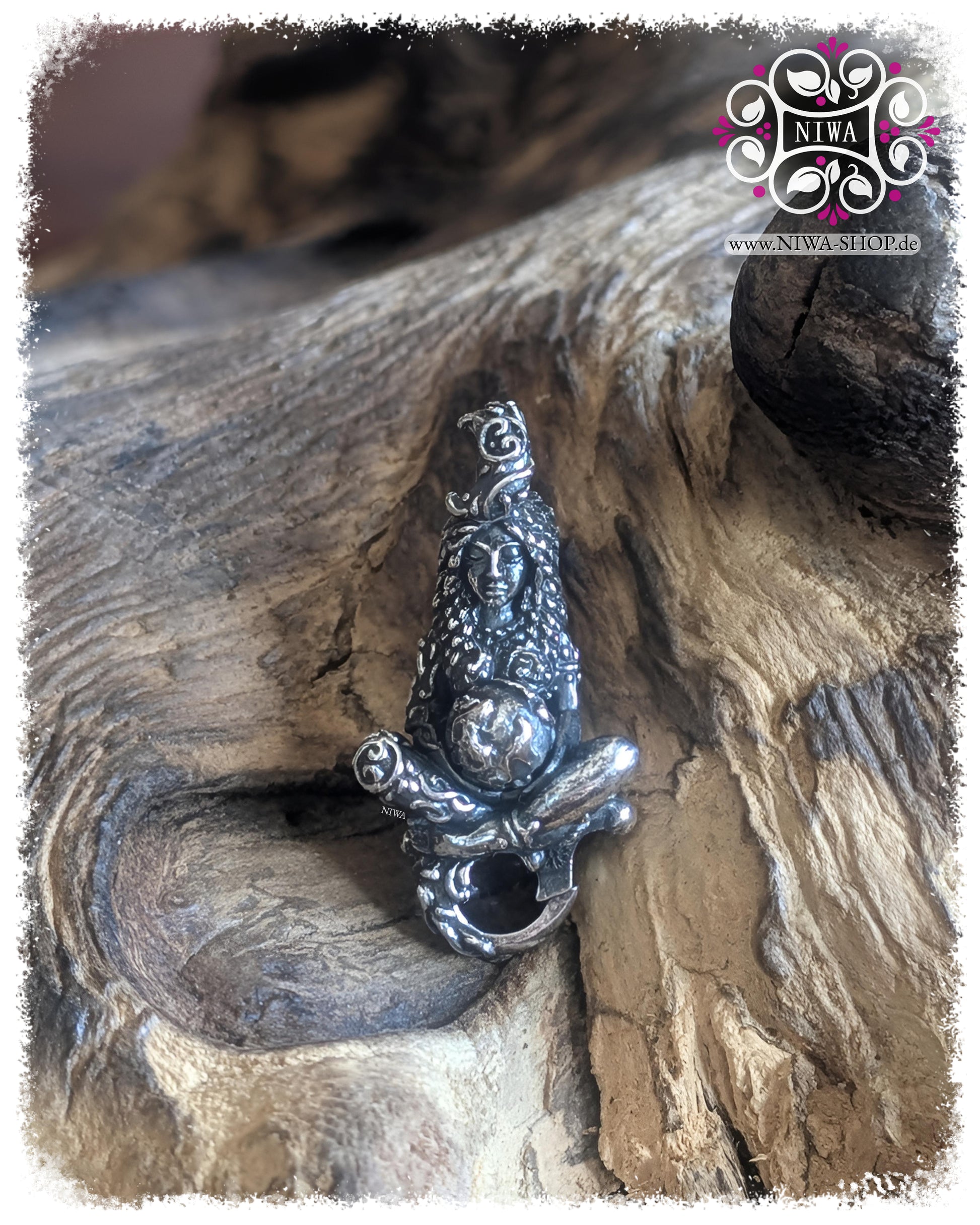 Frontansicht des GAIA MOTHER of LIFE Lock aus 925 SterlingSilber auf naturbelassenem Holz. Die sitzende Frauenfigur hält eine silberne Weltkugel in den Händen. Ihr Gewand aus Blättern, das rankenartige Haar und die oben organisch integrierte Öse sind klar erkennbar.