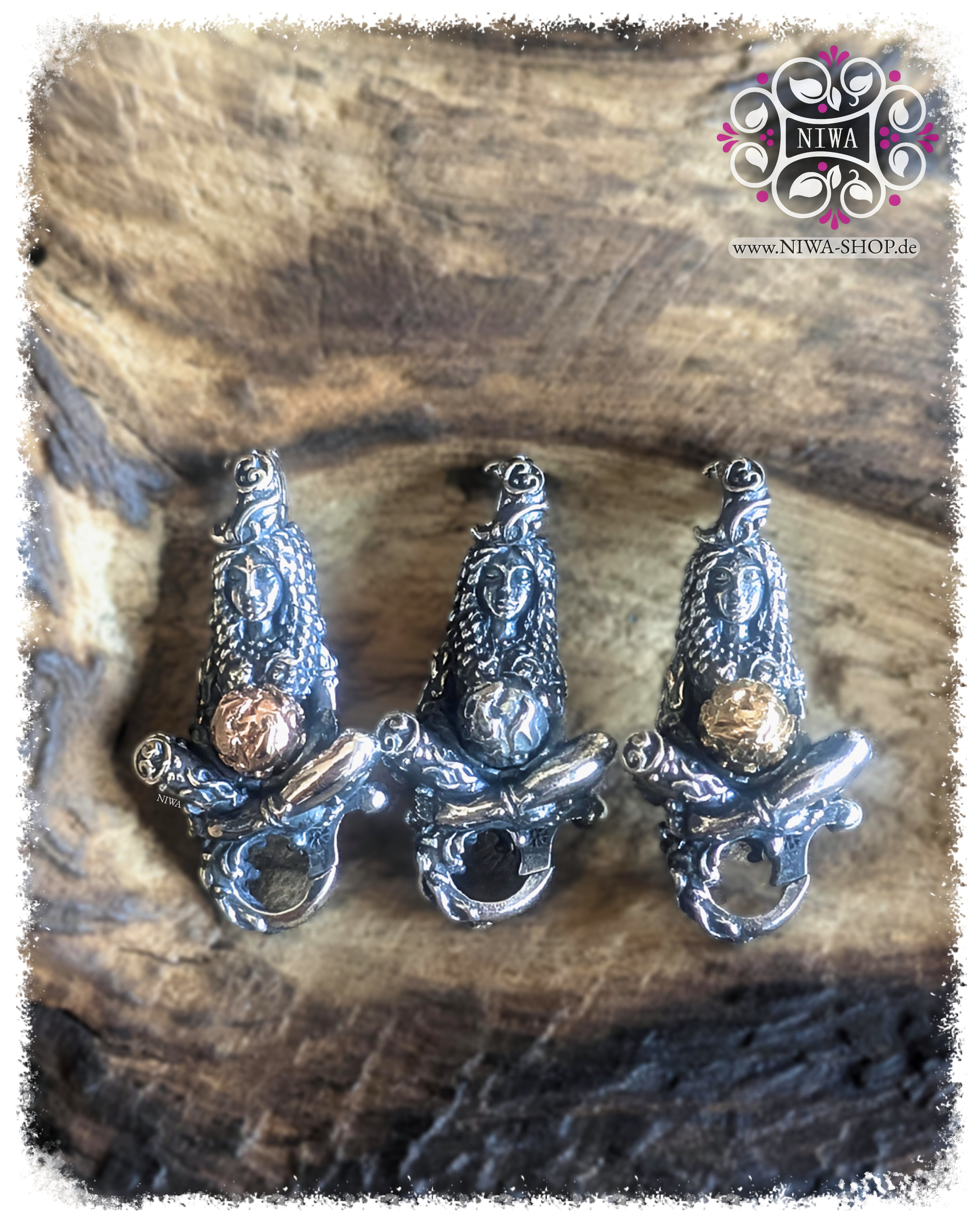 GAIA MOTHER of LIFE Lock von MAMA MALA in drei Varianten auf verwittertem Holz. In der Mitte die Silberversion mit silberner Weltkugel, links die TwoTone Variante mit RoséGold Kugel, rechts die TwoTone Variante mit GelbGold Kugel. Die sitzende Frauenfigur trägt die Welt in den Händen und zeigt organische Blatt, Ranken und Wurzelstrukturen.