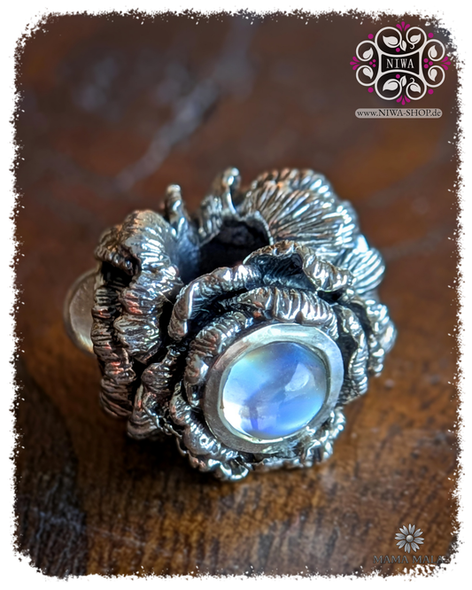 POPPY BLOOM Charm aus massivem 925 SterlingSilber mit 3x Blue Moonstone Cabochon, Frontansicht auf Holz, MAMA MALA by NIWA