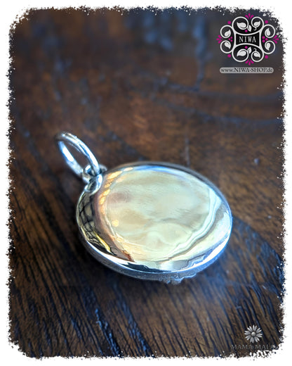 Rückseite des PANG RAM PUENG COIN Dangle aus massivem 925 SterlingSilber, glatt polierte Rückseite mit Öse auf dunklem Holz.