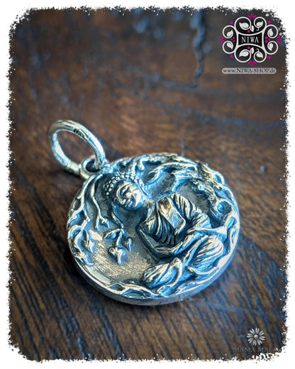 PANG SAMATHI COIN Dangle in seitlicher Ansicht, detailreicher Donnerstagsbuddha aus 925 SterlingSilber mit meditierender Buddha Darstellung und organischem Relief auf dunkler Holzstruktur.