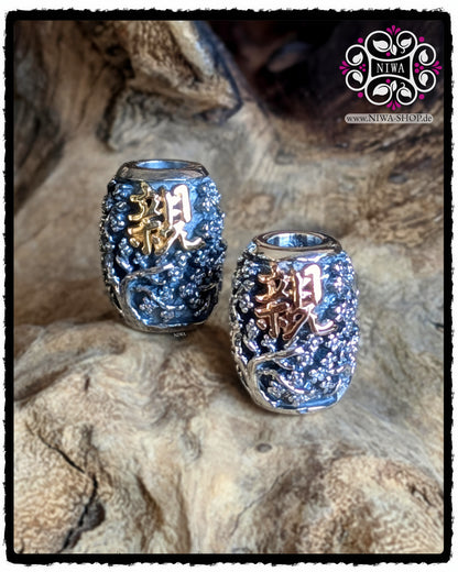 CHINESE GOODWILL BarrelCharm MAMA MALA by NIWA, 925 SterlingSilber Barrel mit SAKURA Relief, Vergleich der Varianten 18K GelbGold und 18K RoséGold Schriftzeichen, beide Barrels nebeneinander auf Holz.