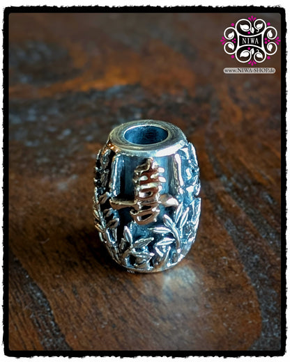 CHINESE JOY BarrelCharm aus 925 SterlingSilber mit 18K RoséGold Schriftzeichen, Frontansicht auf Holzhintergrund, detaillierte BAMBUSBLÄTTER und das erhabene JOY Symbol im Mittelpunkt.