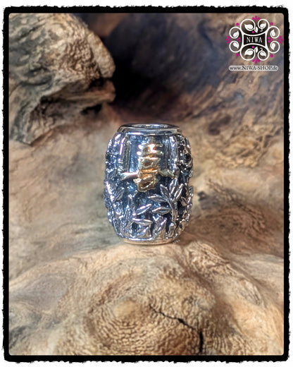 Frontansicht des CHINESE JOY BARRELCHARM von MAMA MALA aus 925 STERLINGSILBER mit dichtem BAMBUSRELIEF und zentralem 18K GELBGOLD Schriftzeichen für JOY, aufgenommen auf natürlichem Holzuntergrund.