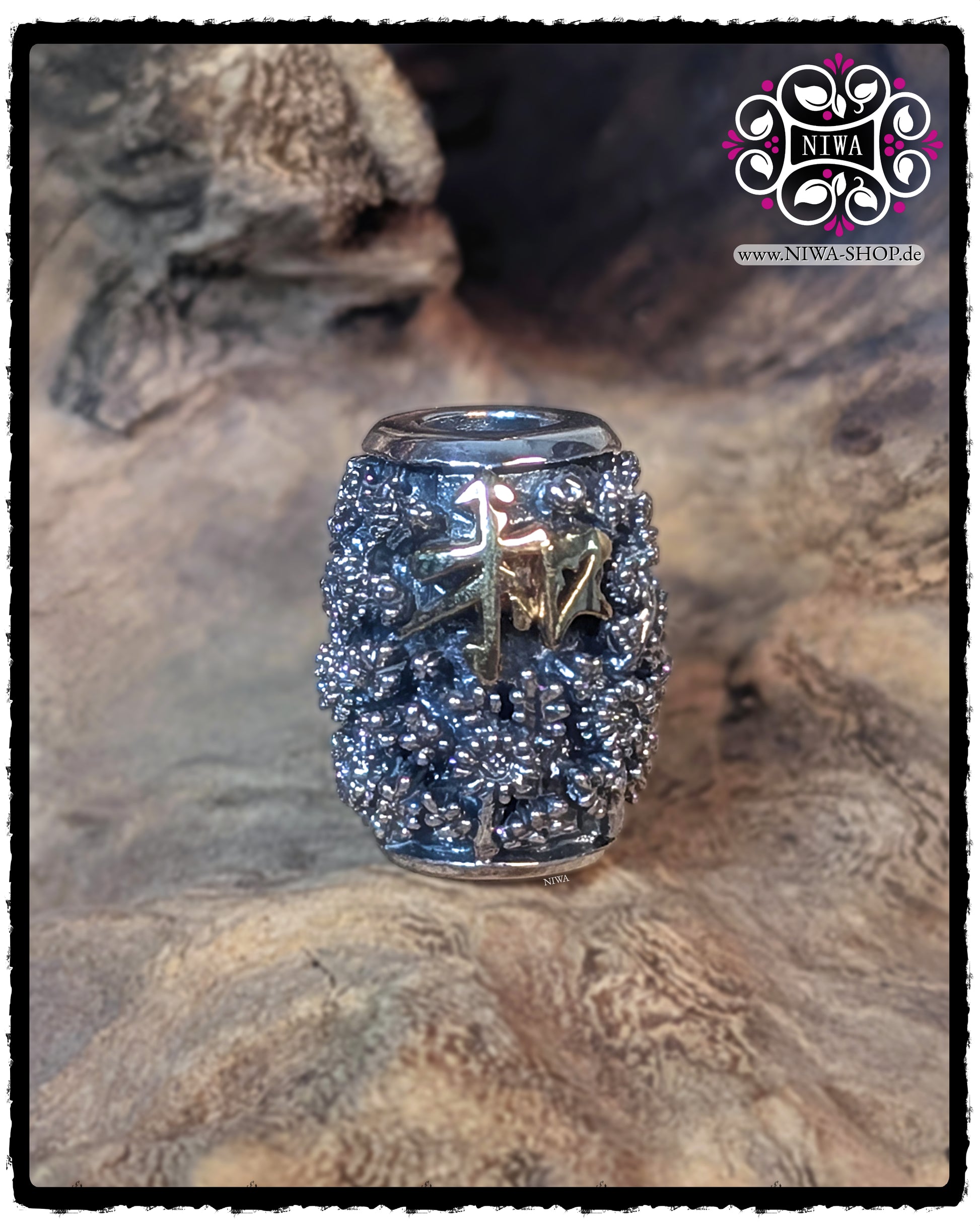 CHINESE PEACE BARRELCHARM aus 925 STERLINGSILBER mit erhabenem CHRYSANTHEMENRELIEF und 18K GELBGOLD SCHRIFTZEICHEN auf der Vorderseite, frontal vor einer strukturierten Holzoberfläche stehend.