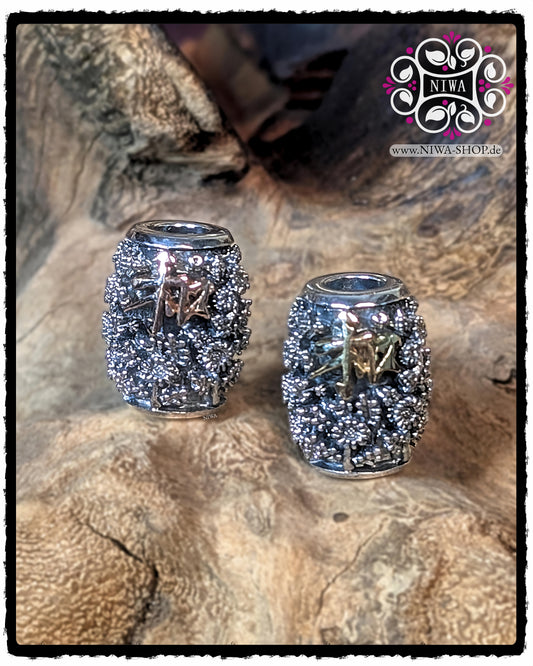 Zwei CHINESE PEACE BARRELCHARMS aus 925 STERLINGSILBER nebeneinander, links mit 18K GELBGOLD SCHRIFTZEICHEN, rechts mit 18K ROSÉGOLD SCHRIFTZEICHEN, beide mit vollflächigem CHRYSANTHEMENRELIEF vor Holzdekor.