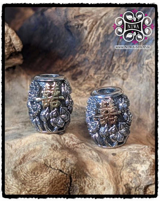 Zwei CHINESE DOUBLE HAPPINESS BarrelCharms nebeneinander, links mit 18K GelbGold Schriftzeichen, rechts mit 18K RoséGold Schriftzeichen, beide mit LOTUS-Blütenrelief vor Holz-Hintergrund.