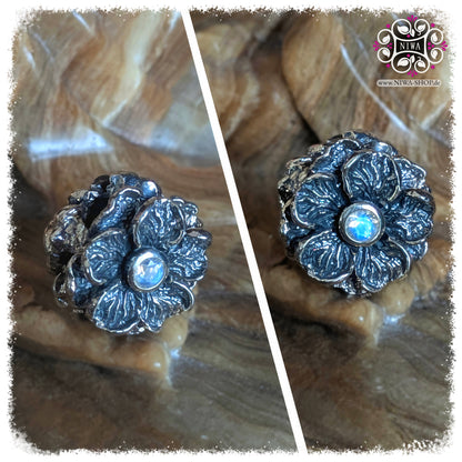BLUER MOONSTONE FORGET ME NOT Charm, NIWABEADS FLORAL GLORY, solid 925 STERLING SILVER, collage with two views, shimmering moonstone in setting, plastic flower with structured surface, stone background.