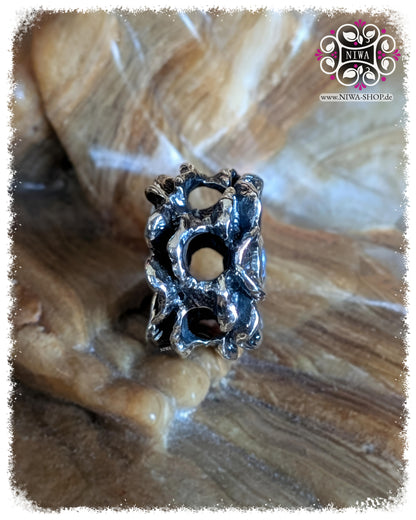 FORGET ME NOT Charm, 925 Sterling Silver, Blue Quartz. Rear view with a view of the construction: several openings for threading through (6 in total), which enable use with multiple bracelets or strands, on a stone surface.