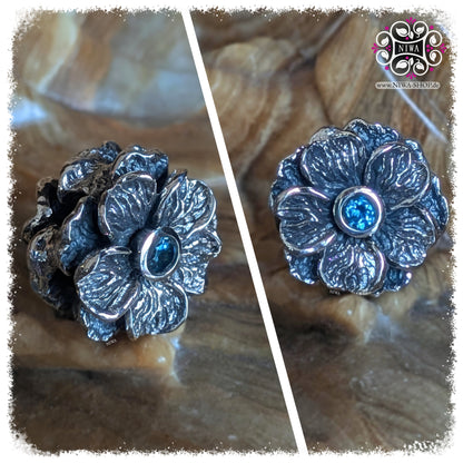 BLUE LONDON TOPAZ FORGET ME NOT Charm, NIWABEADS FLORAL GLORY, solid 925 STERLING SILVER, collage with front view and side view, dark blue gemstone in setting, plastic flower shape, detailed leaf structure.