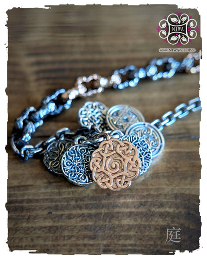 INFINITY COINS DangleSpacer von NIWABeads in TwoTone Roségold mit ornamentalen Silbercoins und zentralem Coin in 14K Roségold, leicht schräg auf Holz dargestellt.