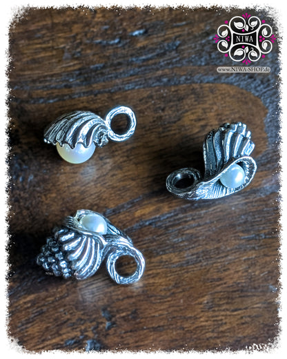 Drei NIWABEADS SEASHELL DANGLES aus der OCEAN Collection, MYSTIC PEARL Serie, 925 STERLINGSILBER, unterschiedliche Muschelformen mit AGOYA PERLEN, gruppiert auf dunklem Holzhintergrund